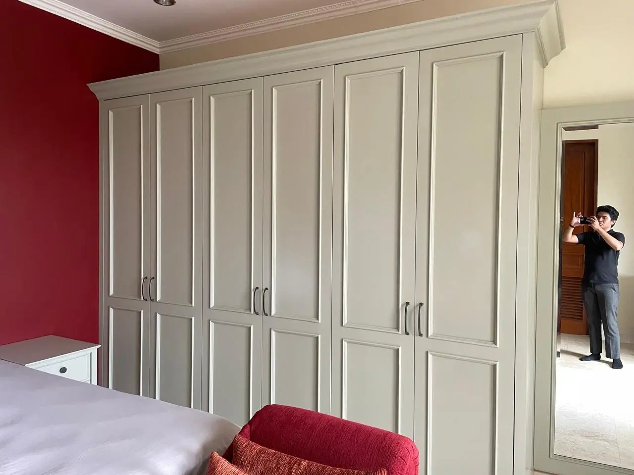 Dresser klasik delapan laci berwarna sage green dengan knob hitam di kamar tidur Andara